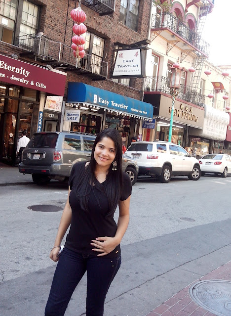 menina caelo preto, calça jeans e blusa preta em uma rua cheia de lojas