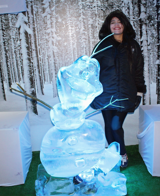 mulher segurando um copo de gelo e olaf de gelo em tamanho real